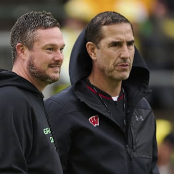 Oct 25, 2025; Eugene, Oregon, USA; Oregon Ducks head coach Dan Lanning, left, and Wisconsin Badgers head coach Luke Fickell talk while watching players warm up before a game at Autzen Stadium. Mandatory Credit: Troy Wayrynen-Imagn Images
