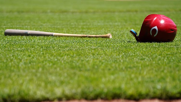 A Cincinnati Reds bat and helmet rest in the infield.