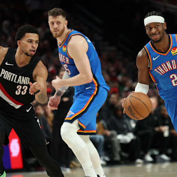 Nov 5, 2025; Portland, Oregon, USA;  Oklahoma City Thunder guard Shai Gilgeous-Alexander (2) dribbles the ball past Portland Trail Blazers forward Toumani Camara (33) as teammate Thunder’s center/forward Isaiah Hartenstein (55) watches during the first half at Moda Center. Mandatory Credit: Jaime Valdez-Imagn Images

