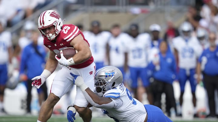 Sep 6, 2025; Madison, Wisconsin, USA; Wisconsin Badgers running back Cade Yacamelli (25) is tackled by Middle Tennessee Blue Raiders defensive tackle Zeion Simpson-Smith (95) during the first half at Camp Randall Stadium. Mandatory Credit: Kayla Wolf-Imagn Images Sep 6, 2025; Madison, Wisconsin, USA; Wisconsin Badgers running back Cade Yacamelli (25) is tackled by Middle Tennessee Blue Raiders defensive tackle Zeion Simpson-Smith (95) during the first half at Camp Randall Stadium. Mandatory Credit: Kayla Wolf-Imagn Images