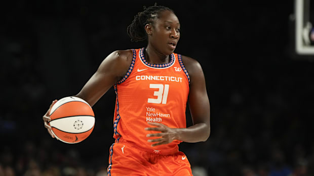 Connecticut Sun center Tina Charles dribbles the ball during a game, wearing an orange jersey with black borders.