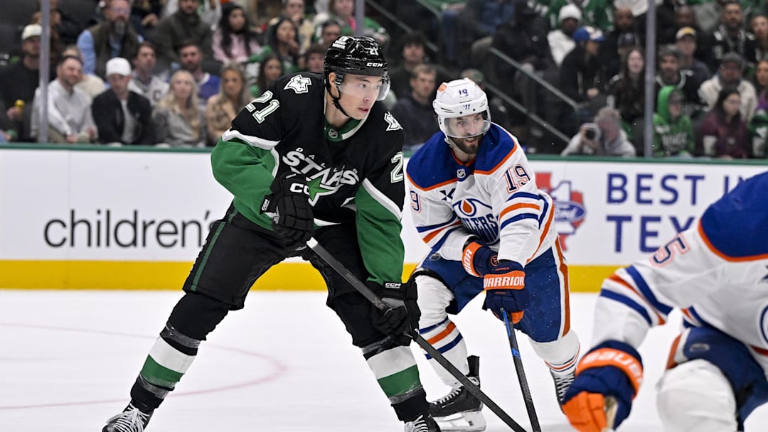 Mar 12, 2026; Dallas, Texas, USA; Dallas Stars left wing Jason Robertson (21) and Edmonton Oilers center Adam Henrique (19) look for the puck during the game between the Stars and the Oilers at the American Airlines Center. Mandatory Credit: Jerome Miron-Imagn Images