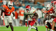Oct 17, 2025; Miami Gardens, Florida, USA; Louisville Cardinals running back Isaac Brown (1) carries the football against Miami Hurricanes linebacker Mohamed Toure (1) and linebacker Wesley Bissainthe (31) during the first quarter at Hard Rock Stadium. Mandatory Credit: Sam Navarro-Imagn Images