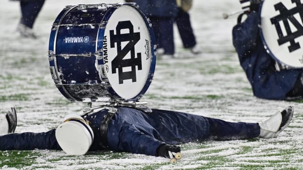 A Notre Dame marching band members does snow angels during a halftime performance in November of 2022.