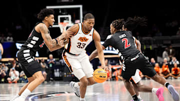 Mar 11, 2025; Kansas City, MO, USA; Oklahoma State Cowboys forward Abou Ousmane (33) drives to the basket around Cincinnati Bearcats guard Jizzle James (2) during the first half at T-Mobile Center. Mandatory Credit: William Purnell-Imagn Images