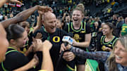 Oregon players mob coach Kelly Graves, center, during his TV interview after upsetting Baylor at Matthew Knight Arena in Eugene.