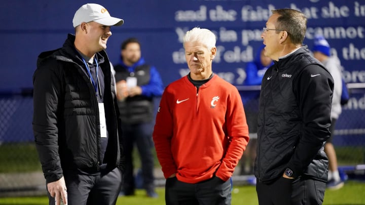 Cincinnati Bengals head coach Zac Taylor, left, talks with Cincinnati Bearcats special teams coordinator and secondary coach Kerry Coombs, center, and head coach Scott Satterfield, right, in the first half of a second-round Division I OHSAA high school football game between the Moeller Crusaders and the St. Xavier Bombers, Friday, Nov. 3, 2023, at St. Xavier High School   s RDI Field in Cincinnati.