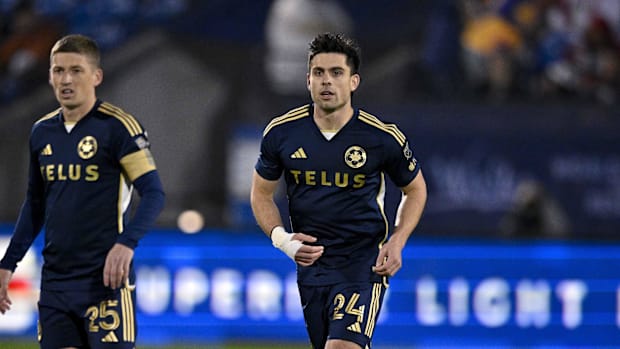 Brian White and Ryan Gauld run during a soccer match. 