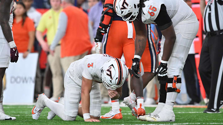 Nov 2, 2024; Syracuse, New York, USA; Virginia Tech Hokies offensive lineman Xavier Chaplin (65) looks after quarterback Collin Schlee (3) who was shaken up on a play against the Syracuse Orange in the fourth quarter at JMA Wireless Dome. Mandatory Credit: Mark Konezny-Imagn Images