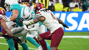 Nov 16, 2025; Madrid, Spain; Miami Dolphins running back De'Von Achane (28) carries the ball defended by Washington Commanders linebacker Bobby Wagner (54) and linebacker Frankie Luvu (4) in the fourth quarter during the 2025 NFL Madrid Game at Santiago Bernabeu Stadium. Mandatory Credit: Kirby Lee-Imagn Images