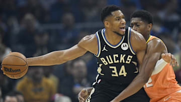 Milwaukee Bucks forward Giannis Antetokounmpo holds the ball beside Cleveland Cavaliers forward De'Andre Hunter.