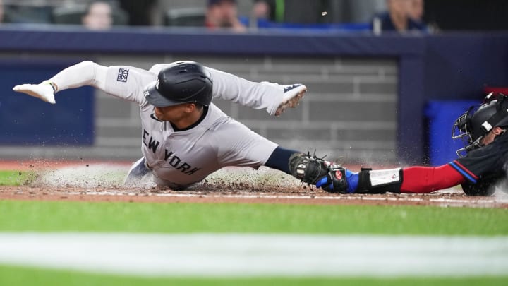 Jun 28, 2024; Toronto, Ontario, CAN; New York Yankees right fielder Juan Soto (22) slides into home plate scoring a run ahead of the tag from Toronto Blue Jays catcher Danny Jansen (9) during the fourth inning at Rogers Centre. Mandatory Credit: Nick Turchiaro-USA TODAY Sports
