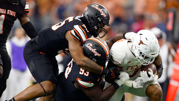 Texas tight end Ja'Tavion Sanders is tackled by Oklahoma State's Collin Clay.