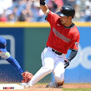Jun 26, 2025; Cleveland, Ohio, USA; Cleveland Guardians left fielder Steven Kwan (38) slides into second with a double as Toronto Blue Jays second baseman Andres Gimenez (0) is late with the tag during the first inning at Progressive Field.