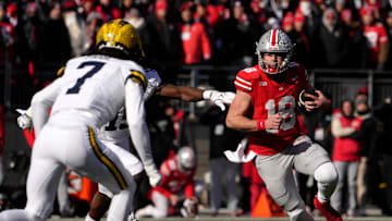 Ohio State Buckeyes quarterback Will Howard (18) is pursued by Michigan Wolverines defensive back Makari Paige (7) and Michigan Wolverines linebacker Ernest Hausmann (15 )during the first half of Saturday’s NCAA Division I football game at Ohio Stadium.