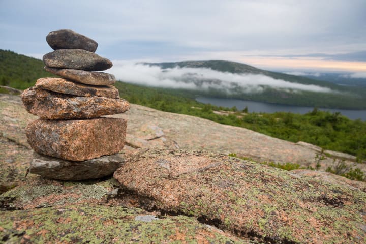 Cairn on rocks with Low clouds over lake in Acadia National Park, Maine