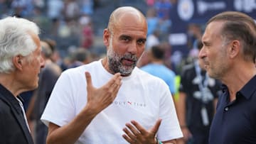 Jul 27, 2024; New York, NY, USA; Manchester City head coach Pep Guardiola speaks with Marty Edelman, left, and AC Milan owner Gerry Cardinale before the match between AC Milan and Manchester City at Yankee Stadium. Mandatory Credit: Lucas Boland-Imagn Images