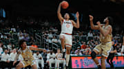 Dec 21, 2024; Coral Gables, Florida, USA; Miami Hurricanes guard Matthew Cleveland (0) drives to the basket past Mount St. Mary's Mountaineers forward Jedy Cordilia (14) and guard Javon Ervin (23) during the second half at Watsco Center. Mandatory Credit: Sam Navarro-Imagn Images
