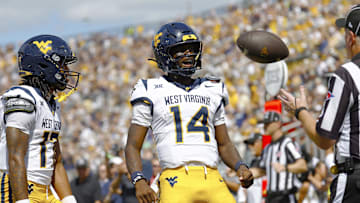 Oct 18, 2025; Orlando, Florida, USA; West Virginia Mountaineers quarterback Khalil Wilkins (14) flexes after scoring a touchdown in the first half against the Central Florida Knights at Acrisure Bounce House. Mandatory Credit: Russell Lansford-Imagn Images