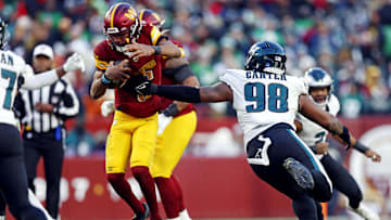 Dec 22, 2024; Landover, Maryland, USA; Washington Commanders quarterback Jayden Daniels (5) runs the ball against Philadelphia Eagles defensive tackle Jalen Carter (98) during the fourth quarter at Northwest Stadium. Mandatory Credit: Peter Casey-Imagn Images