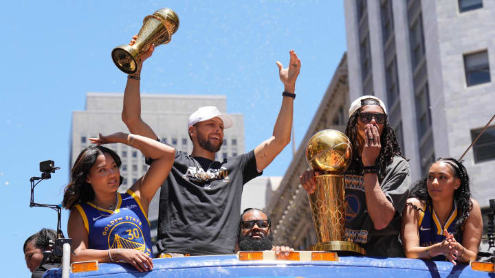 Jun 20, 2022; San Francisco, CA, USA; Golden State Warriors guard Stephen Curry (middle left) gestures while standing with wife Ayesha (far left) and guard Damion Lee (middle right) and his wife Sydel Curry (far right) during the Golden State Warriors championship parade in downtown San Francisco. Mandatory Credit: Darren Yamashita-USA TODAY Sports
