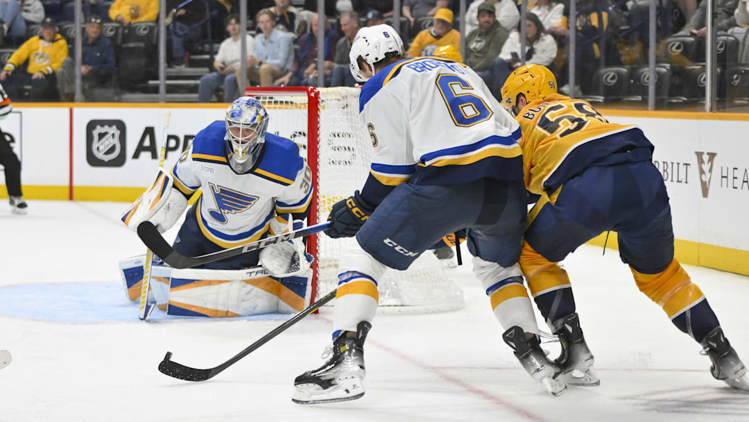 Mar 27, 2025; Nashville, Tennessee, USA;  St. Louis Blues goaltender Joel Hofer (30) and defenseman Philip Broberg (6) blocks the shot of Nashville Predators left wing Michael Bunting (58) during the third period at Bridgestone Arena. Mandatory Credit: Steve Roberts-Imagn Images