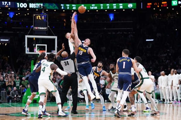 A jump ball between Denver Nuggets center Nikola Jokic (15) and Boston Celtics center Kristaps Porzingis (8).