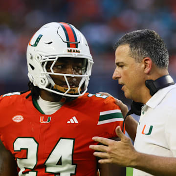 Sep 7, 2024; Miami Gardens, Florida, USA; Miami Hurricanes head coach Mario Cristobal talks to Miami Hurricanes linebacker Malik Bryant (24) during the second quarter at Hard Rock Stadium. Mandatory Credit: Sam Navarro-Imagn Images