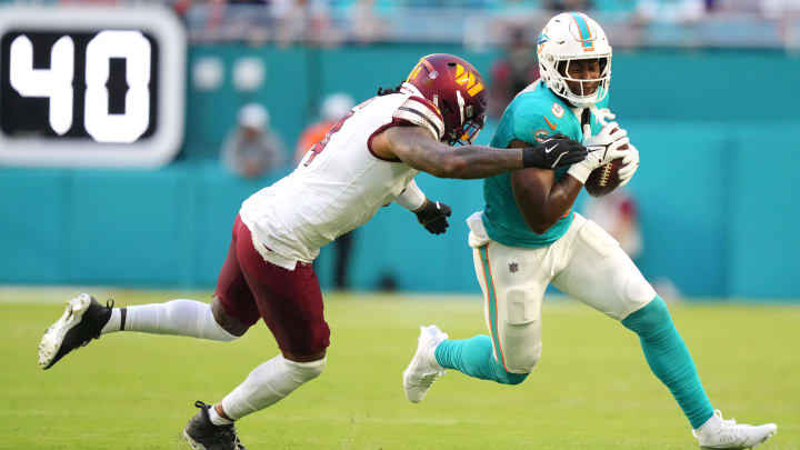 Miami Dolphins tight end Jonnu Smith (9) runs as Washington Commanders linebacker Frankie Luvu (4) drives him out of bounds during the first quarter at Hard Rock Stadium.