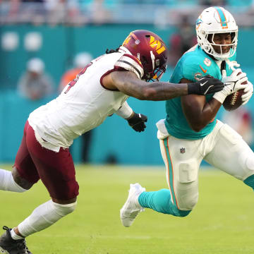 Miami Dolphins tight end Jonnu Smith (9) runs as Washington Commanders linebacker Frankie Luvu (4) drives him out of bounds during the first quarter of a preseason game at Hard Rock Stadium.