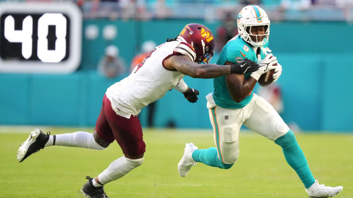 Miami Dolphins tight end Jonnu Smith (9) runs as Washington Commanders linebacker Frankie Luvu (4) drives him out of bounds during the first quarter of a preseason game at Hard Rock Stadium.