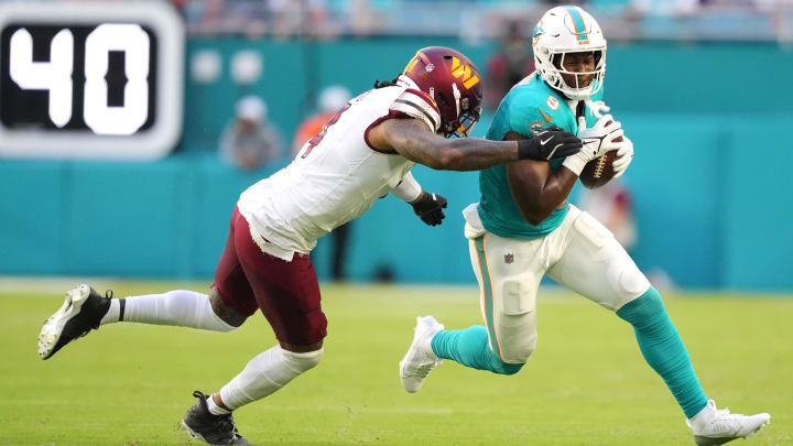 Aug 17, 2024; Miami Gardens, Florida, USA;  Miami Dolphins tight end Jonnu Smith (9) runs as Washington Commanders linebacker Frankie Luvu (4) drives him out of bounds during the first quarter at Hard Rock Stadium.