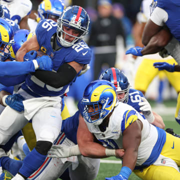 Dec 31, 2023; East Rutherford, New Jersey, USA; New York Giants running back Saquon Barkley (26) is tackled by Los Angeles Rams defensive tackle Aaron Donald (99) during the second half at MetLife Stadium. Mandatory Credit: Vincent Carchietta-USA TODAY Sports