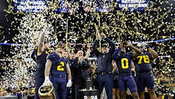 Michigan head coach Jim Harbaugh lifts up the trophy as players and coaches celebrate after 34-13 win over Washington to win the national championship game at NRG Stadium in Houston on Monday, Jan. 8, 2024.