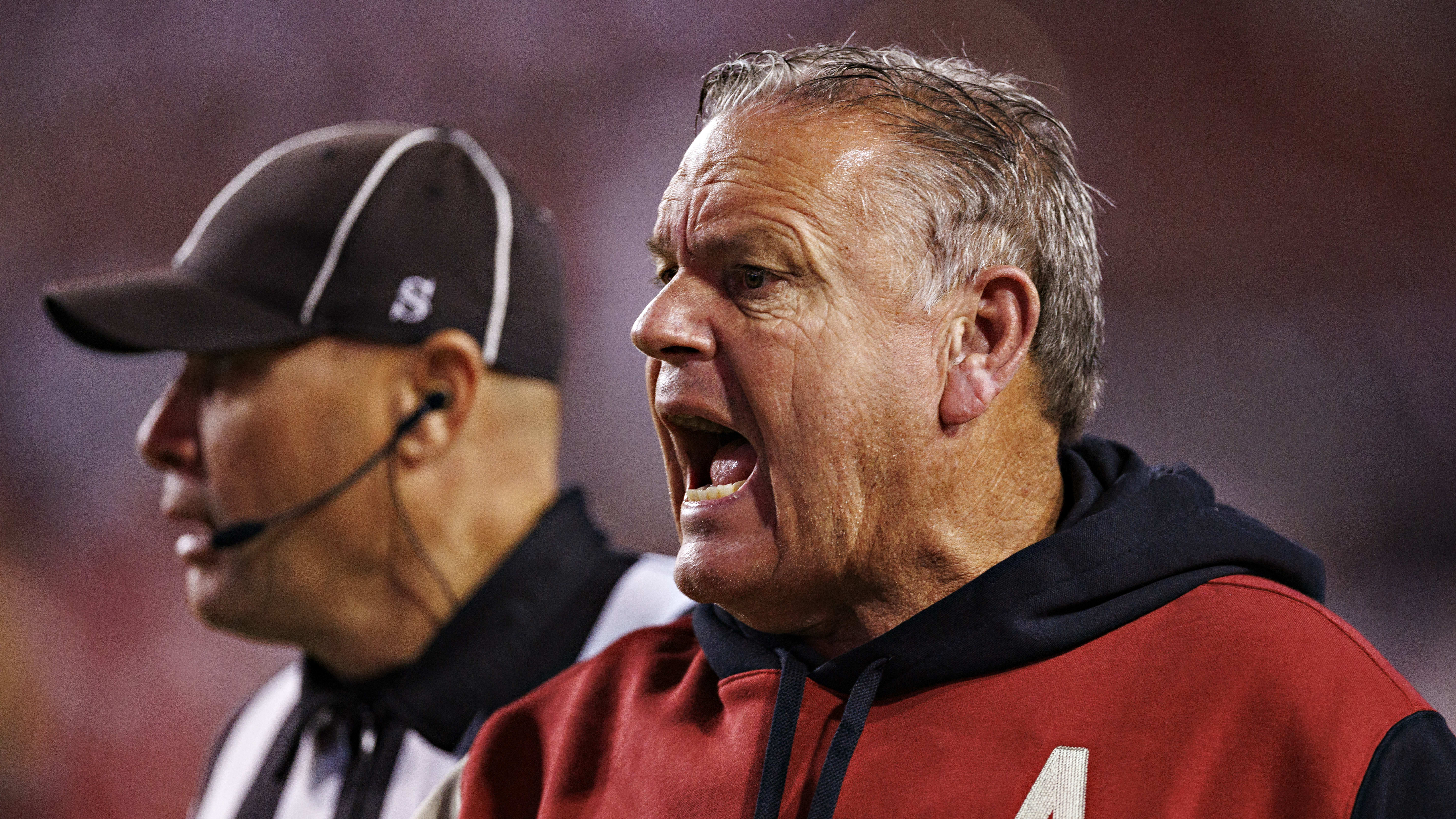 Arkansas coach Sam Pittman yells across the field while a referee looks on.