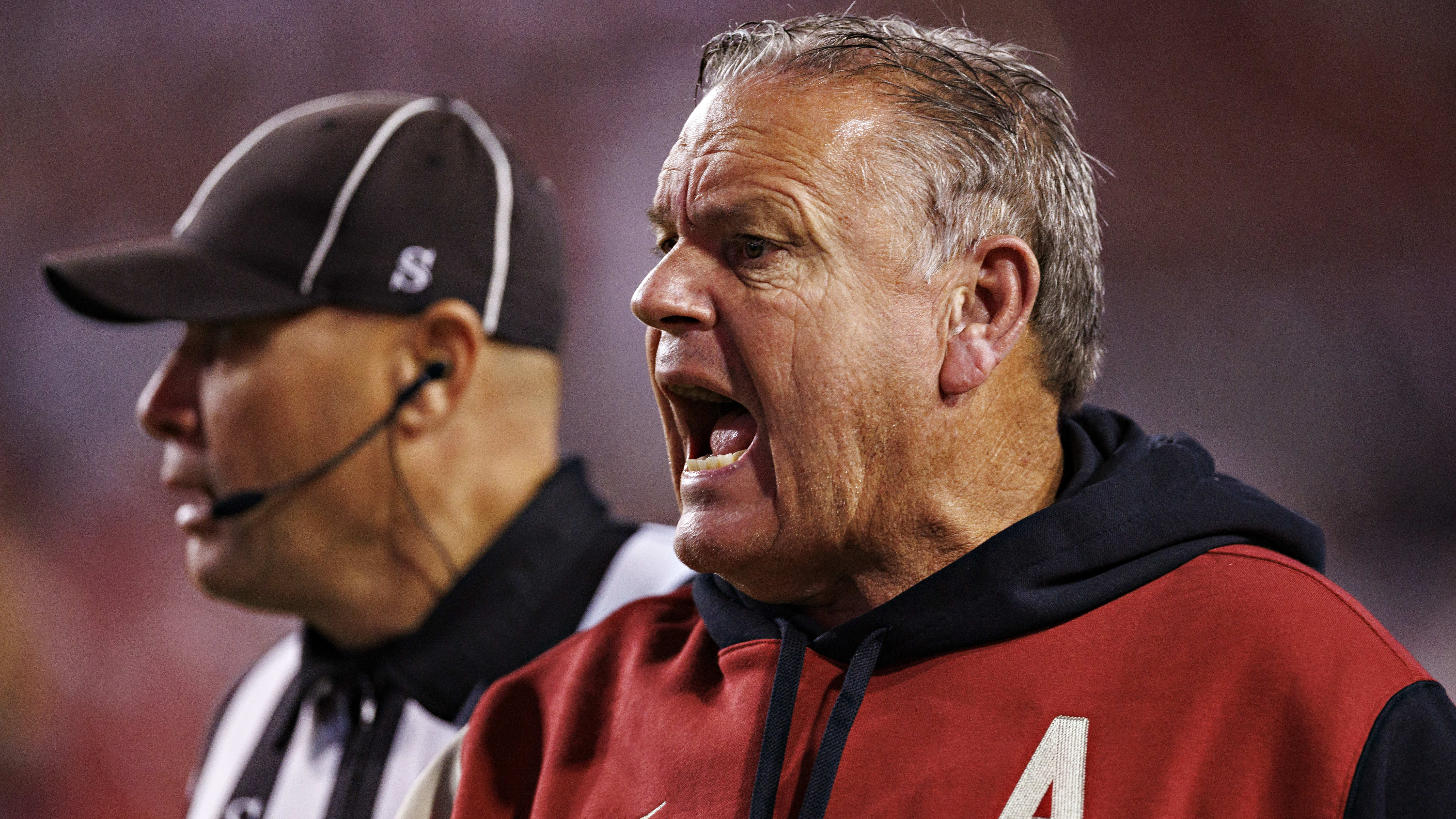 Sam Pittman yells to his team while a referee looks on.