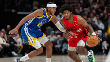 Oct 23, 2024; Portland, Oregon, USA;  Portland Trailblazers guard Scoot Henderson (00) dribbles the ball against Golden State Warriors shooting guard Moses Moody (4) during the first half at Moda Center. Mandatory Credit: Stephen Brashear-Imagn Images