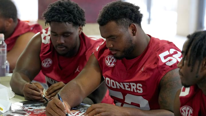 Oklahoma Sooners defensive lineman Damonic Williams signs posters during Meet the Sooners Day