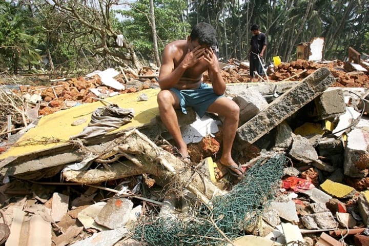 A man sits atop wreckage left behind after the 2004 Indian Ocean tsunami struck Sri Lanka.