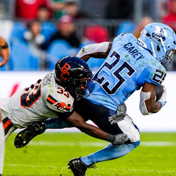 Jun 9, 2024; Toronto, Ontario, CAN; BC Lions defensive back Emmanuel Rugamba (33) tackles Toronto Argonauts running back Ka'Deem Carey (25) at BMO Field. Mandatory Credit: Kevin Sousa-Imagn Images