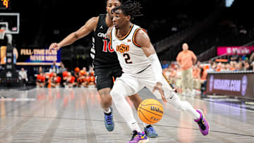 Mar 11, 2025; Kansas City, MO, USA; Oklahoma State Cowboys guard Arturo Dean (2) drives to the basket around Cincinnati Bearcats guard Josh Reed (10) during the first half at T-Mobile Center.