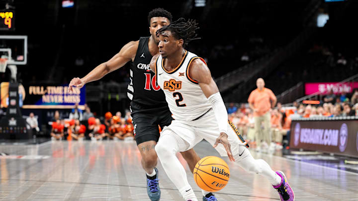 Mar 11, 2025; Kansas City, MO, USA; Oklahoma State Cowboys guard Arturo Dean (2) drives to the basket around Cincinnati Bearcats guard Josh Reed (10) during the first half at T-Mobile Center. Mandatory Credit: William Purnell-Imagn Images Mar 11, 2025; Kansas City, MO, USA; Oklahoma State Cowboys guard Arturo Dean (2) drives to the basket around Cincinnati Bearcats guard Josh Reed (10) during the first half at T-Mobile Center. Mandatory Credit: William Purnell-Imagn Images