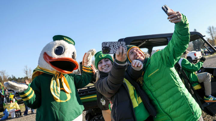 The Duck takes photos with with Oregon fans as they tailgate before the annual rivalry game on Friday, Nov. 24, 2023 at Autzen Stadium in Eugene, Ore.