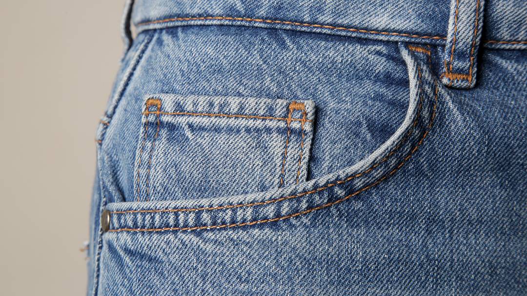 Tiny front pocket on denim pants, close up. Tiny front pocket on denim pants, close up.