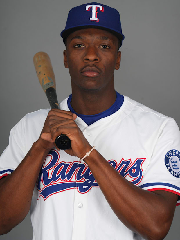 Sebastian Walcott in a white jersey with blue and red lettering and a blue hat posing for media day with a bat.