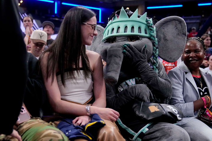 Indiana Fever's Caitlin Clark sits with New York Liberty mascot Ellie the Elephant ahead of the WNBA All-Star 3-point contes