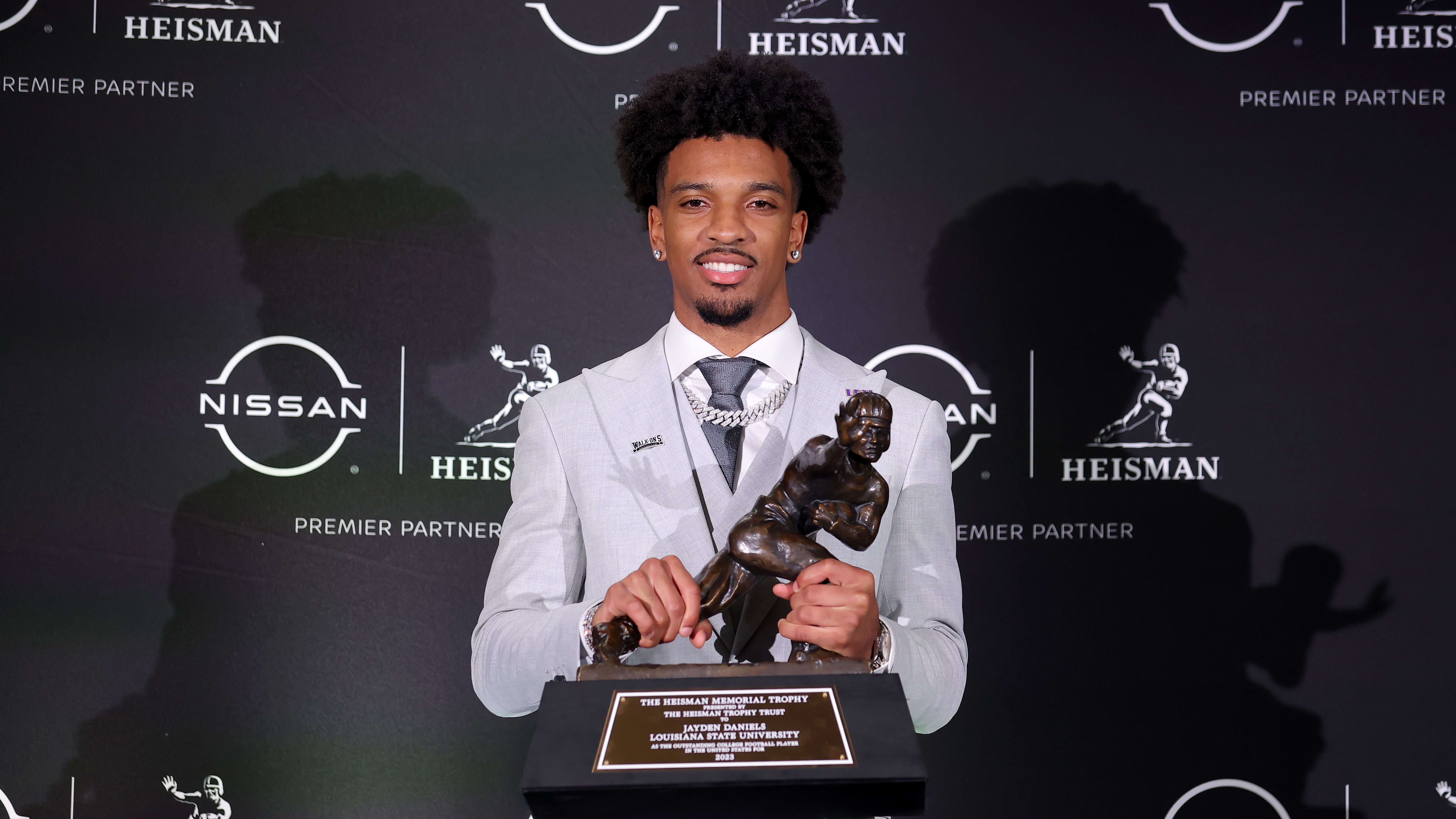 LSU Tigers quarterback Jayden Daniels poses for photos with the Heisman trophy.