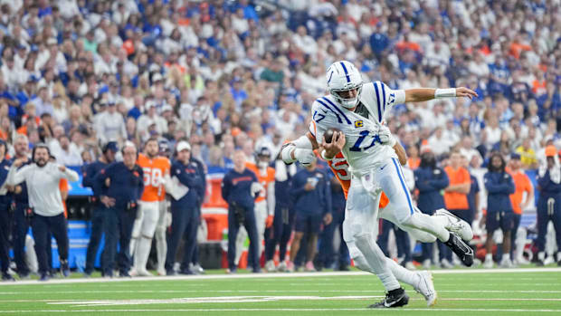 Colts quarterback Daniel Jones (white and blue uniform) tries to escape a tackler.