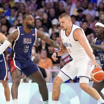 Jul 28, 2024; Villeneuve-d'Ascq, France; Serbia power forward Nikola Jokic (15) dribbles against United States guard Lebron James (6) and guard Jrue Holiday (12) in the first quarter during the Paris 2024 Olympic Summer Games at Stade Pierre-Mauroy.