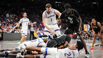 Mar 12, 2025; Kansas City, MO, USA; Kansas Jayhawks forward KJ Adams Jr. (24) and UCF Knights guard Jordan Ivy-Curry (0) go after a loose ball in overtime at T-Mobile Center. Mandatory Credit: William Purnell-Imagn Images